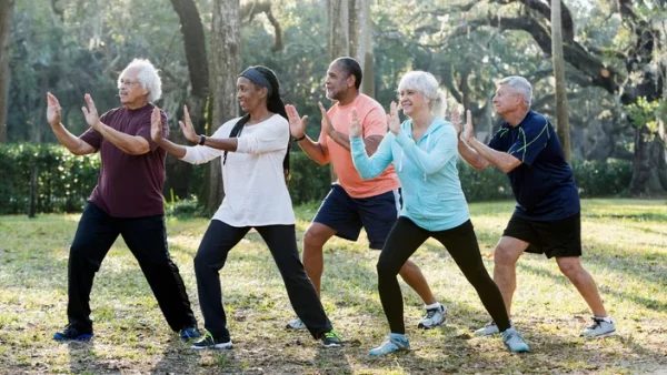 A group of elderly people practicing outdoor yoga, symbolizing endurance and a positive spirit.